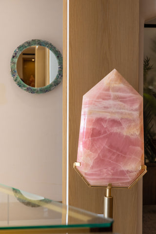 Pink crystal on a stand with a mirror and glass table in the background