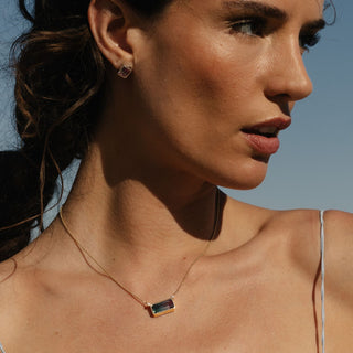 Bi-color tourmaline and diamond necklace in 14k yellow gold worn close to neck, portrait crop.