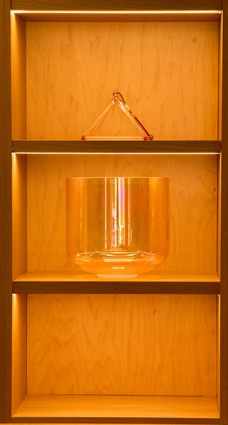 Crone goddess supergrade bowl displayed with crystal pyramid on atelier shelving, warm light.
