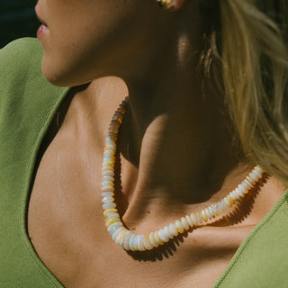 Woman wearing Sanamama Ethiopian white opal beaded necklace, raw crystal healing jewelry with 18k gold