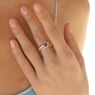 Pink tourmaline heart signet ring in gold worn with stacking band, close hand detail.