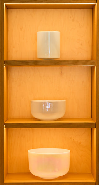 Three sacred singing bowls including larimar on three-tier lit atelier shelving, full display.
