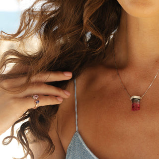 Sapphire pinky ring in 14k rose gold worn with portal necklace, portrait lifestyle shot.