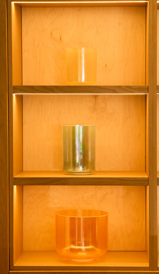 Three-bowl alchemy singing bowl collection on lit atelier shelves, morph bowl center.
