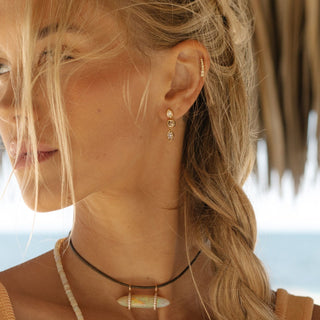 White, brown and yellow diamond drop earrings in gold worn, side profile outdoor light.