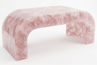 Arched rose quartz crystal bench with mosaic pink stone surface, product shot on white.
