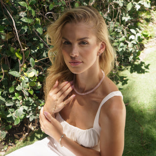 Model wearing raw rose quartz necklace in natural outdoor setting, earth mother healing crystal jewelry