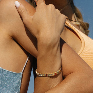 14k gold tennis bracelet featuring aquamarine and pink tourmaline stones, close lifestyle shot.