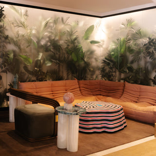 Sanamama sanctuary lounge with curved sectional sofa, crystal instruments, and botanical wall mural.